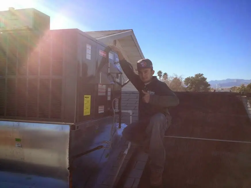 HVAC technician performing Air Duct Repair on a rooftop unit in Henderson